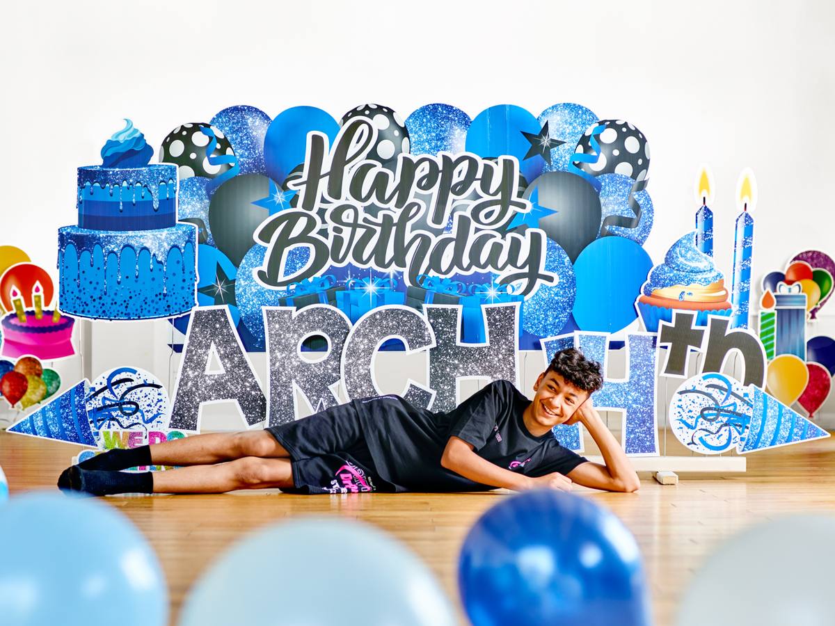 Boy lying in front of his Happy Birthday Arch 14th display