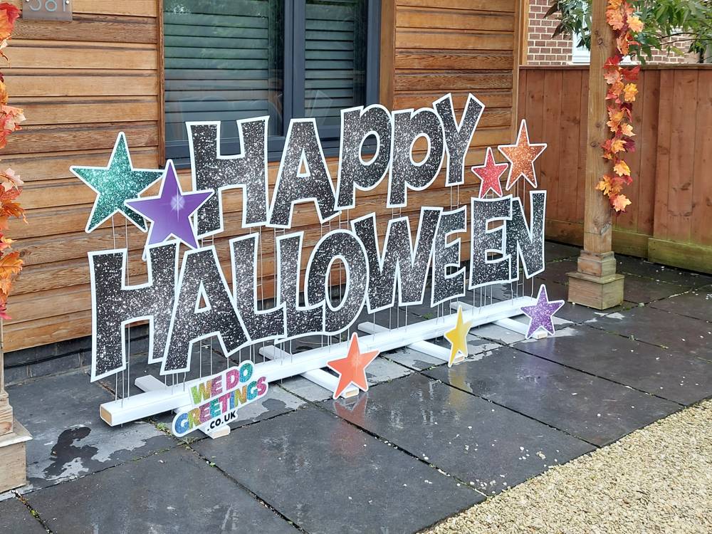 Happy Halloween in black glitter letters with coloured stars on a front porch