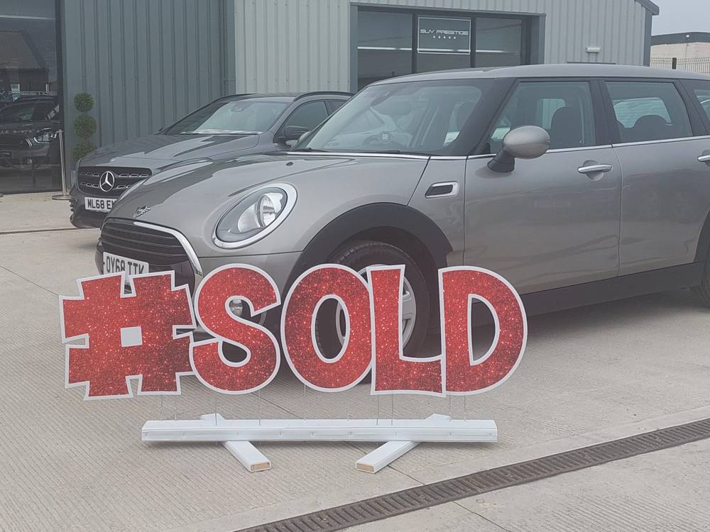 #SOLD in red glitter letters in front of a car on a dealership forecourt