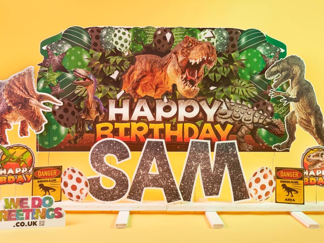 Dinosaur theme: T-rex backdrop with Happy Birthday Sam in glitter letters
